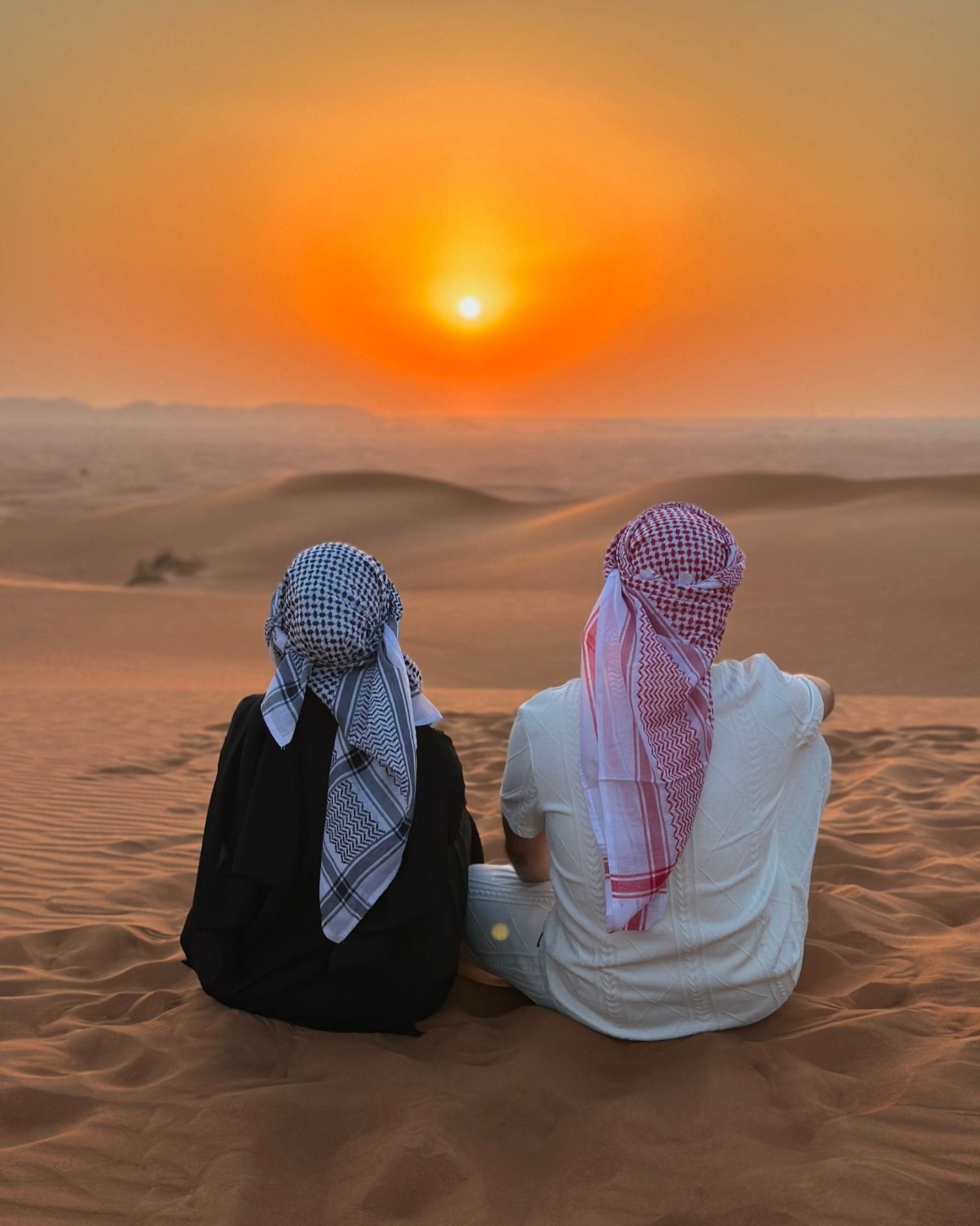 Couple watching the desert sunset over the Arabian dunes